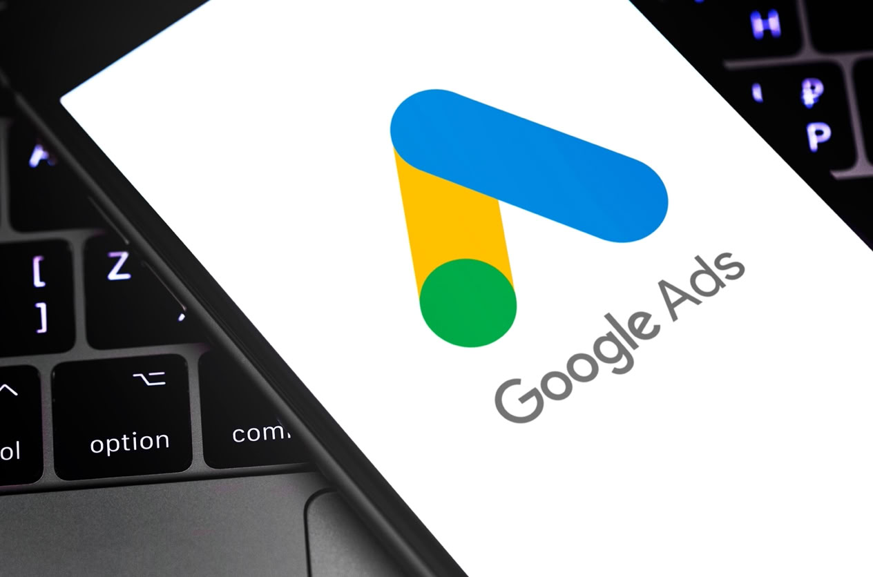 Smartphone mit Google Ads-Logo auf dem Bildschirm, liegt auf einer Laptop-Tastatur.